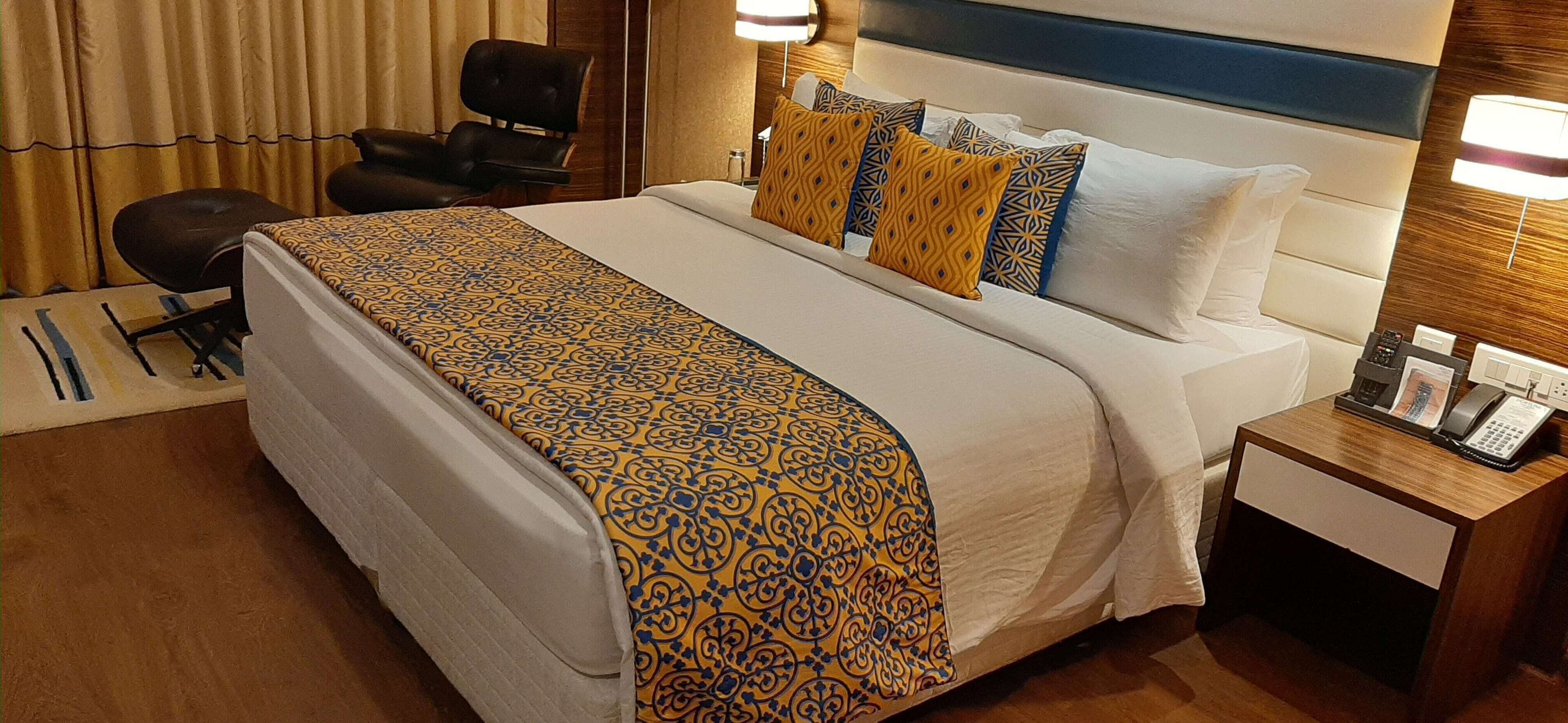 A hotel room with a large bed, a bedside table with a phone, and a chair.