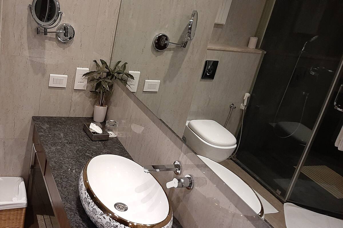 Een moderne badkamer met twee toiletten, een wastafel, een spiegel en een douche.