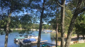 Un parque junto al lago con barcos amarrados, mesas de picnic y un parque infantil.