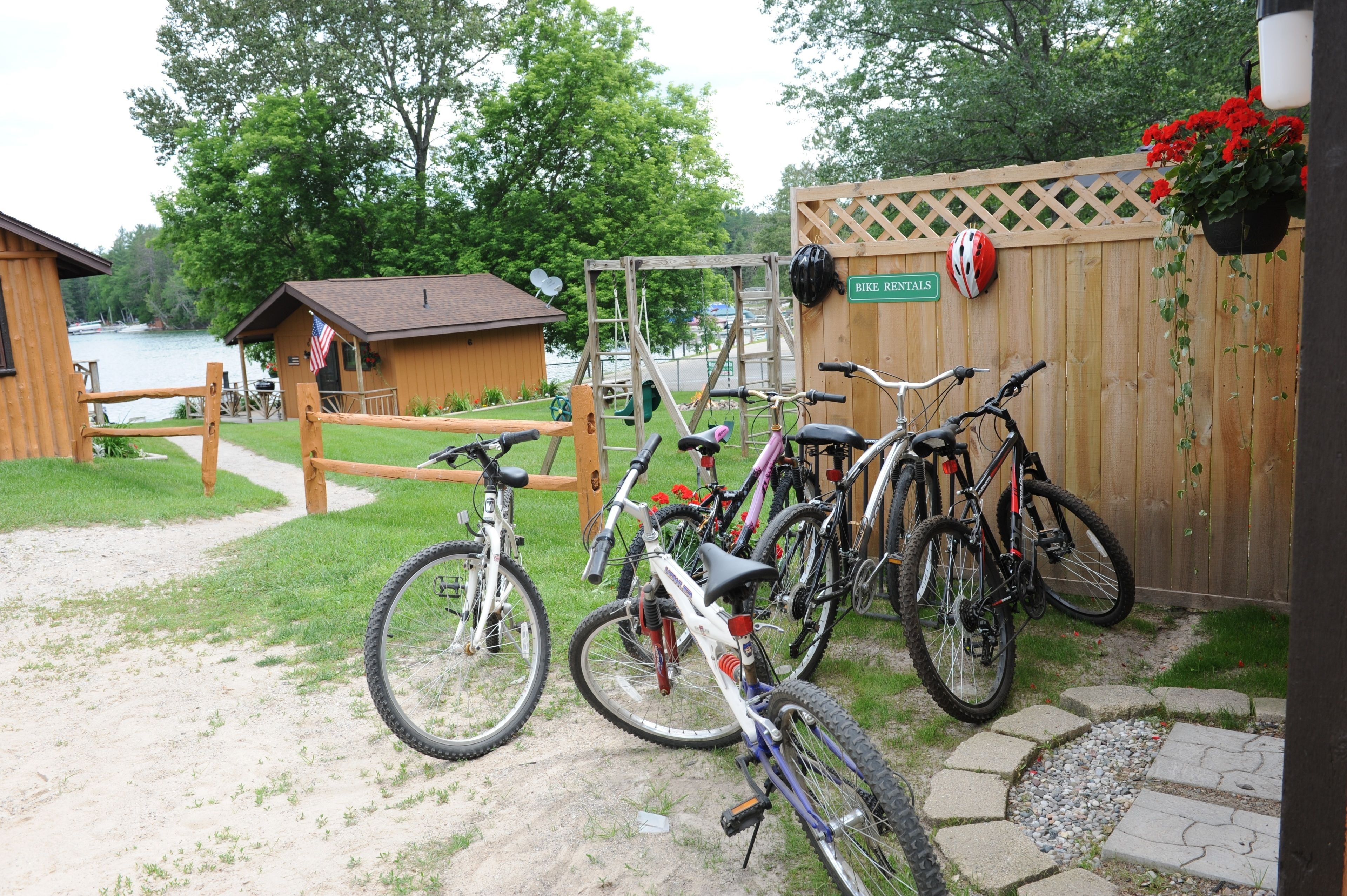 A wooden fence with a bike rental sign, a wooden deck, and a view of a lake.