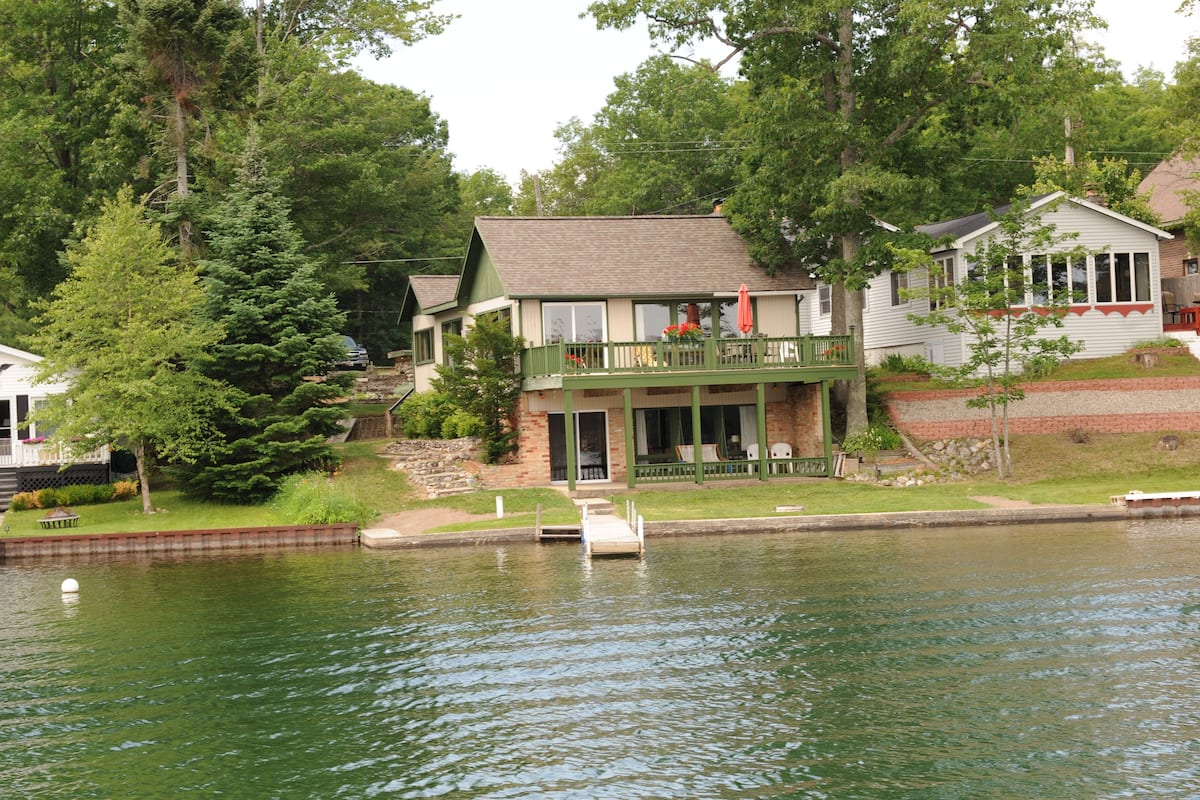 A lakeside cabin with a dock, a deck, and a small garden area.