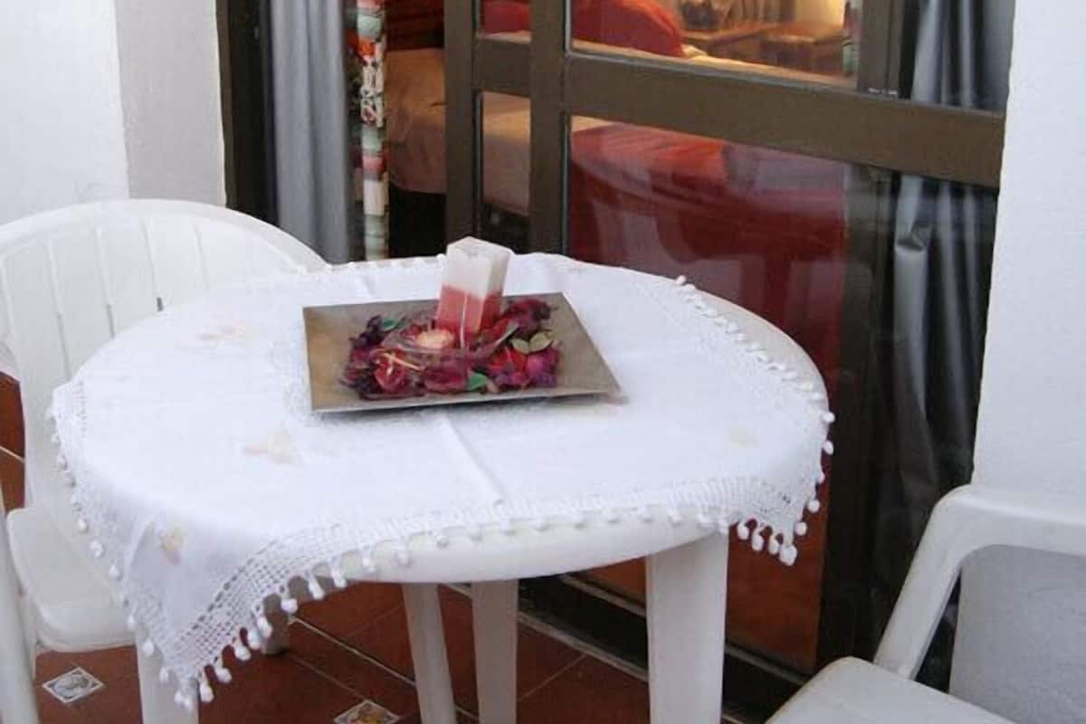 Una mesita redonda con mantel de encaje blanco y un plato de comida.