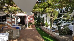 A garden patio with a brick pathway, white drapes, and potted plants. - El Tío Mateo (Marbella)