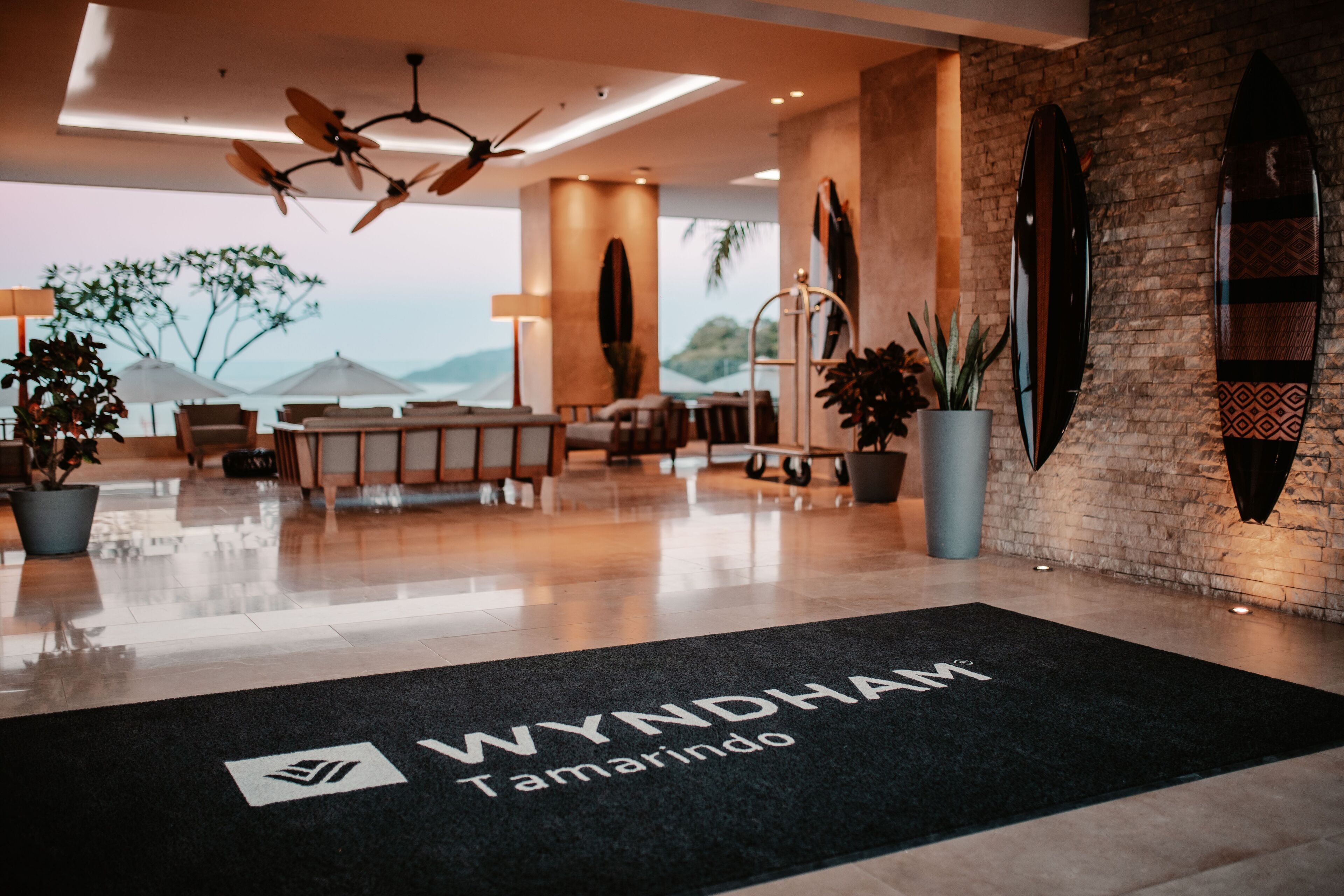 A modern hotel lobby with a black carpet displaying the name 'WYNDHAM Tamarindo'.