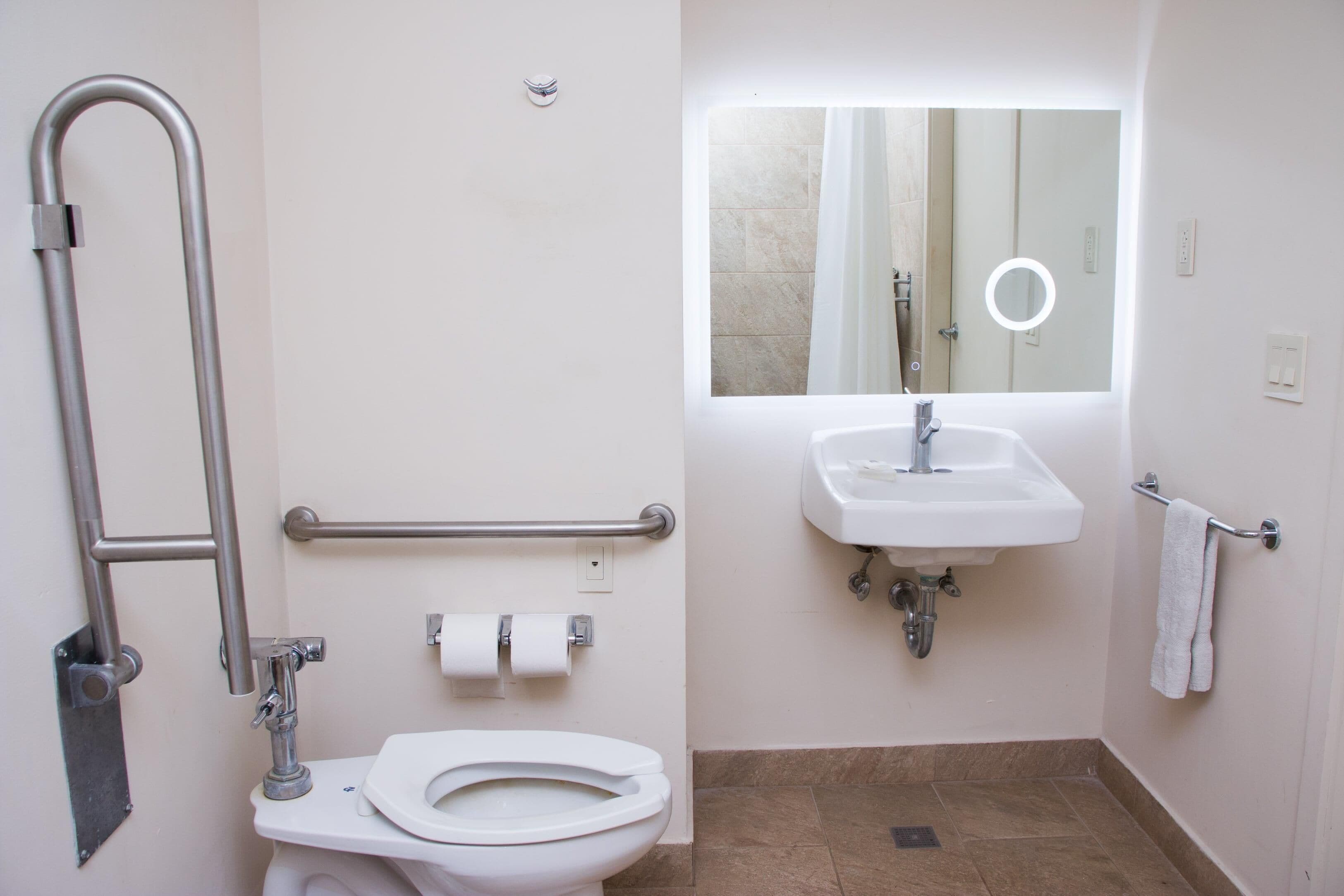 A bathroom with a white toilet, a sink, a mirror, and a shower area.