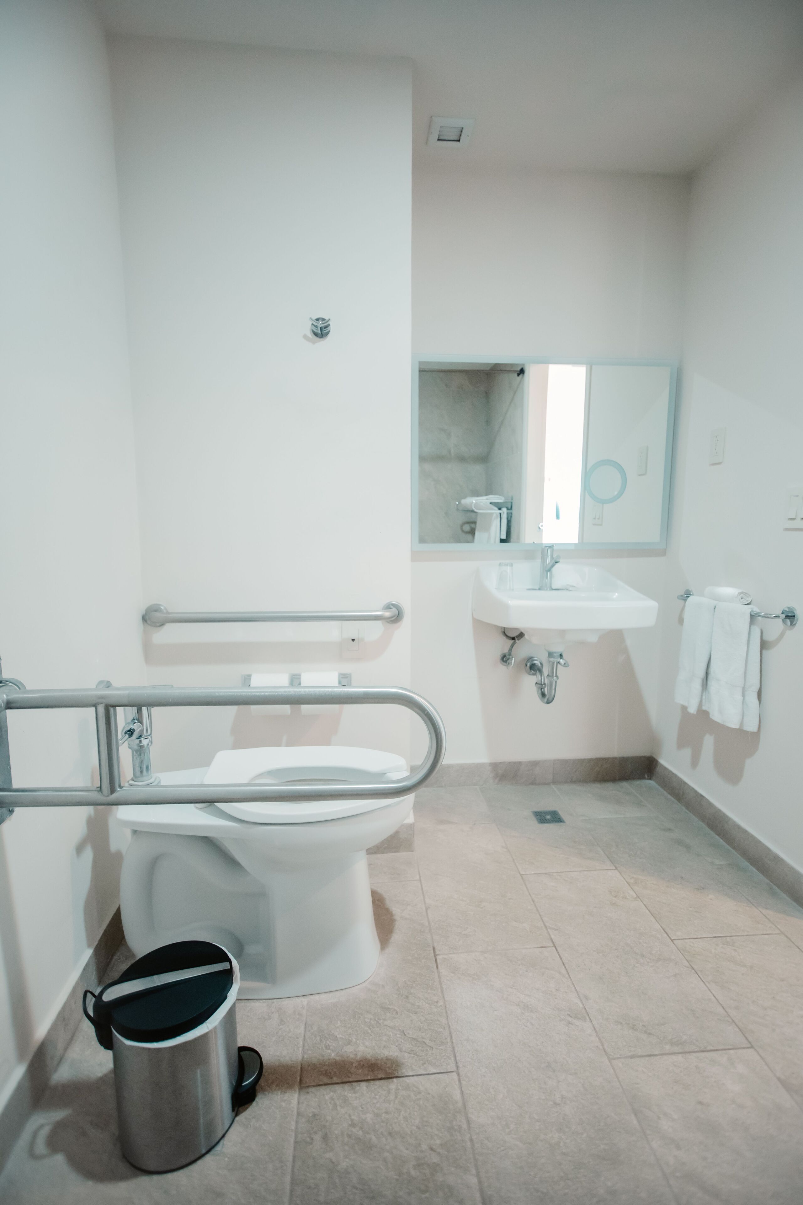 Een badkamer met toilet, wastafel en handgreep.