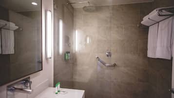 Un baño moderno con ducha, lavamanos y espejo.