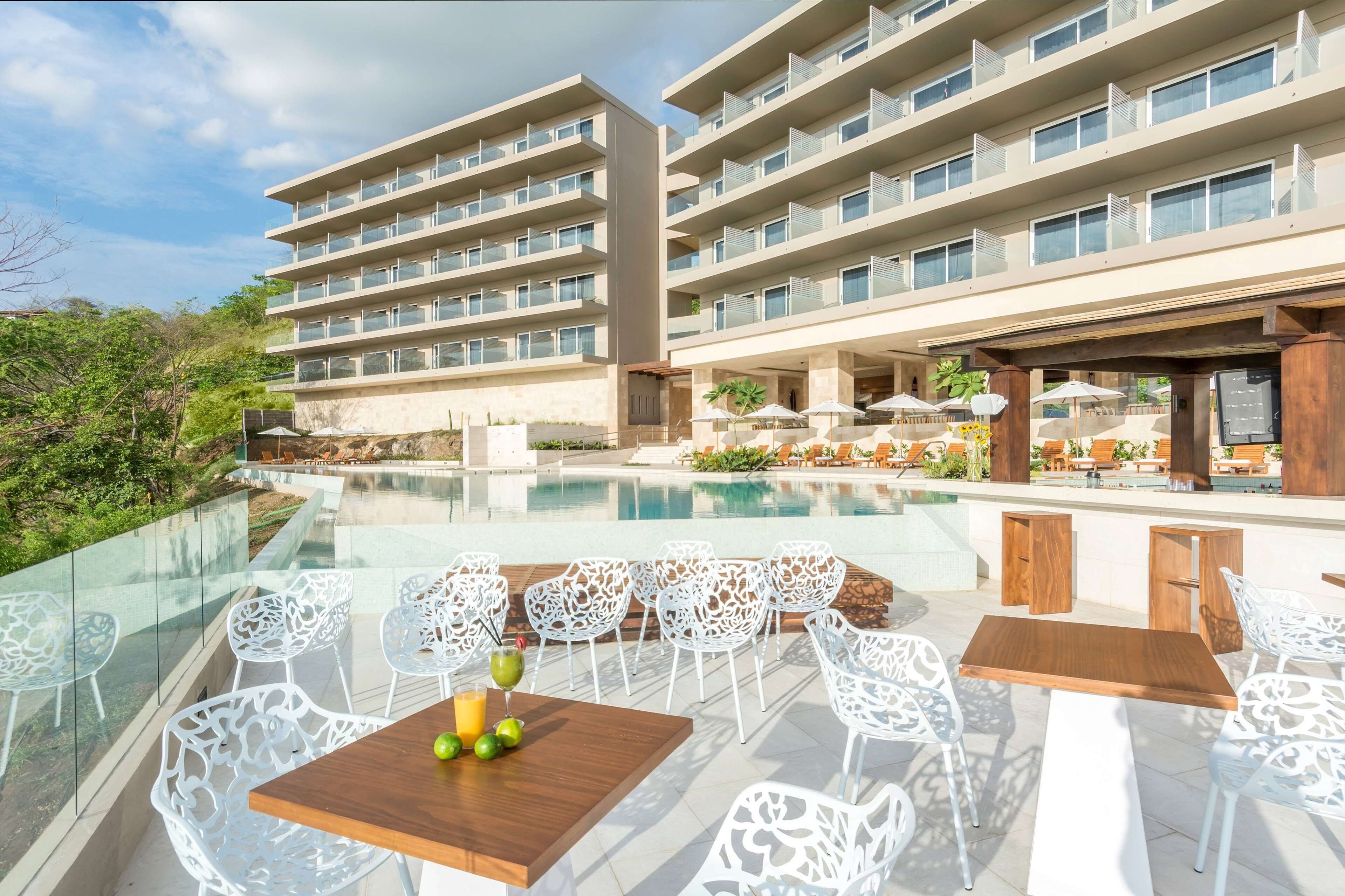 A hotel with a pool, outdoor seating, and a modern design.
