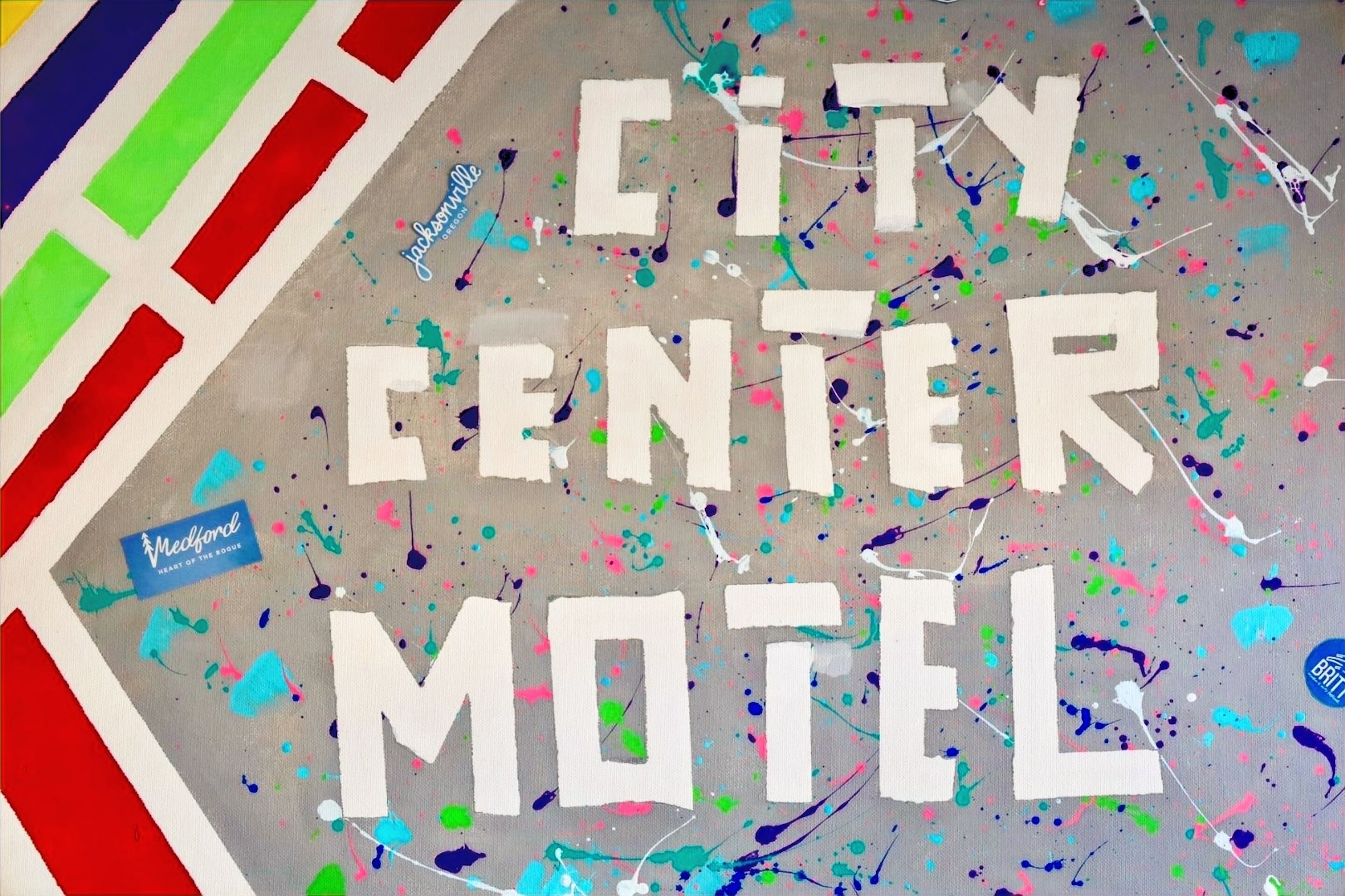 A sign for the City Center Motel with a colorful, abstract design and splatter paint.