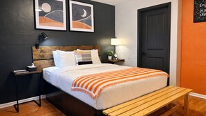 Ein Schlafzimmer mit einem Bett, Nachttischen, einer Bank und Kunstwerken an der Wand.
