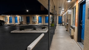 Ein Motel mit mehreren blauen Türen, einem Parkplatz und einer kleinen Gartenanlage.