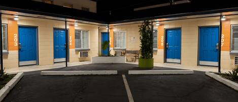 A building with numbered doors, a bench, and a potted plant in the center.