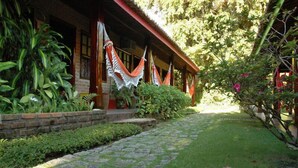 Edifici tradicional amb un porxo cobert, camí de pedra i vegetació exuberant.