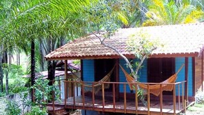 A small, rustic wooden structure with a tiled roof, surrounded by lush greenery. - Pousada Quinta do Caju (Cairu)