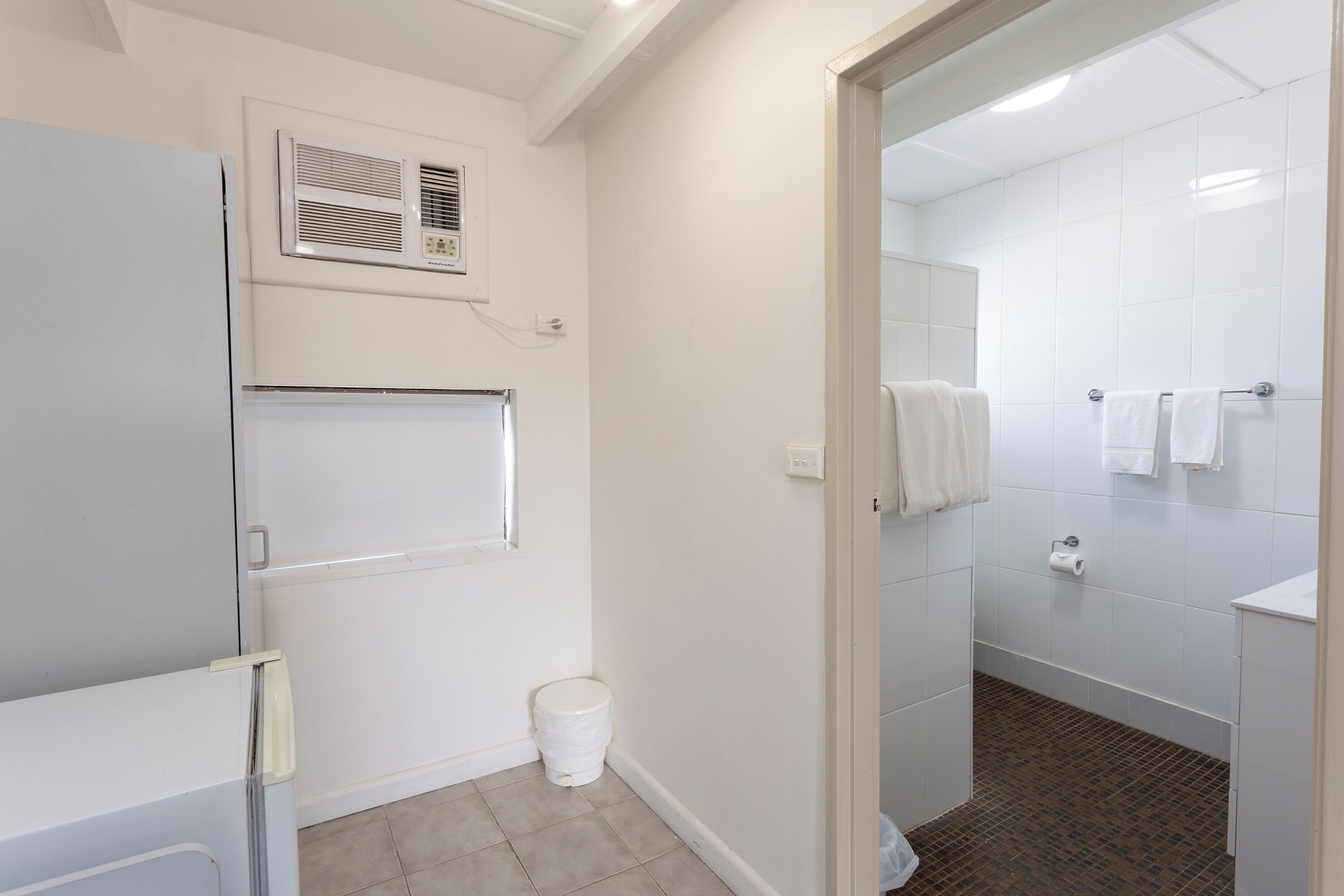 A bathroom with white tiles, a toilet, a sink, and a shower area.