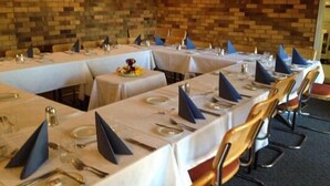 A restaurant with multiple tables set for dining, featuring white tablecloths and blue napkins. - Fig Tree Motel (Narrandera)