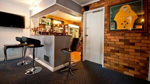 A modern interior with a bar area, seating, and a brick wall with a framed picture. - Fig Tree Motel (Narrandera)