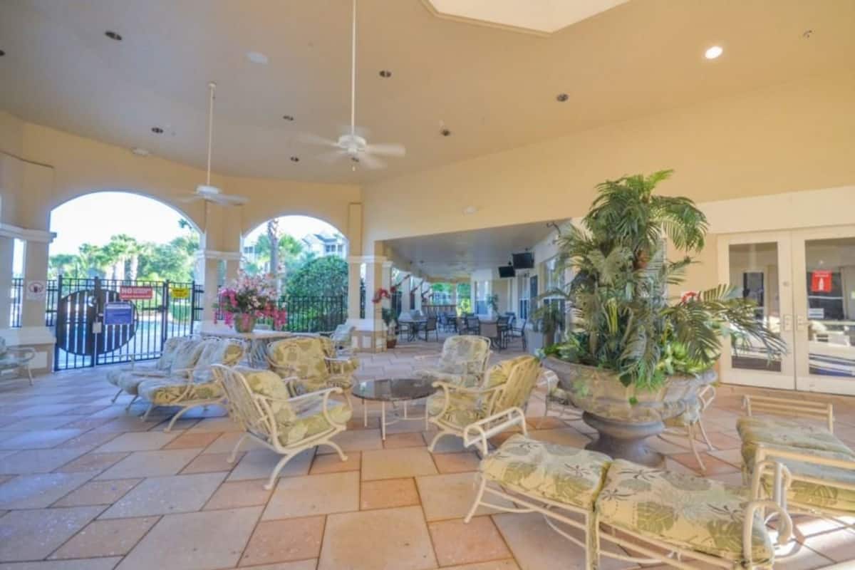 An indoor patio area with wicker furniture, a central table, and potted plants.