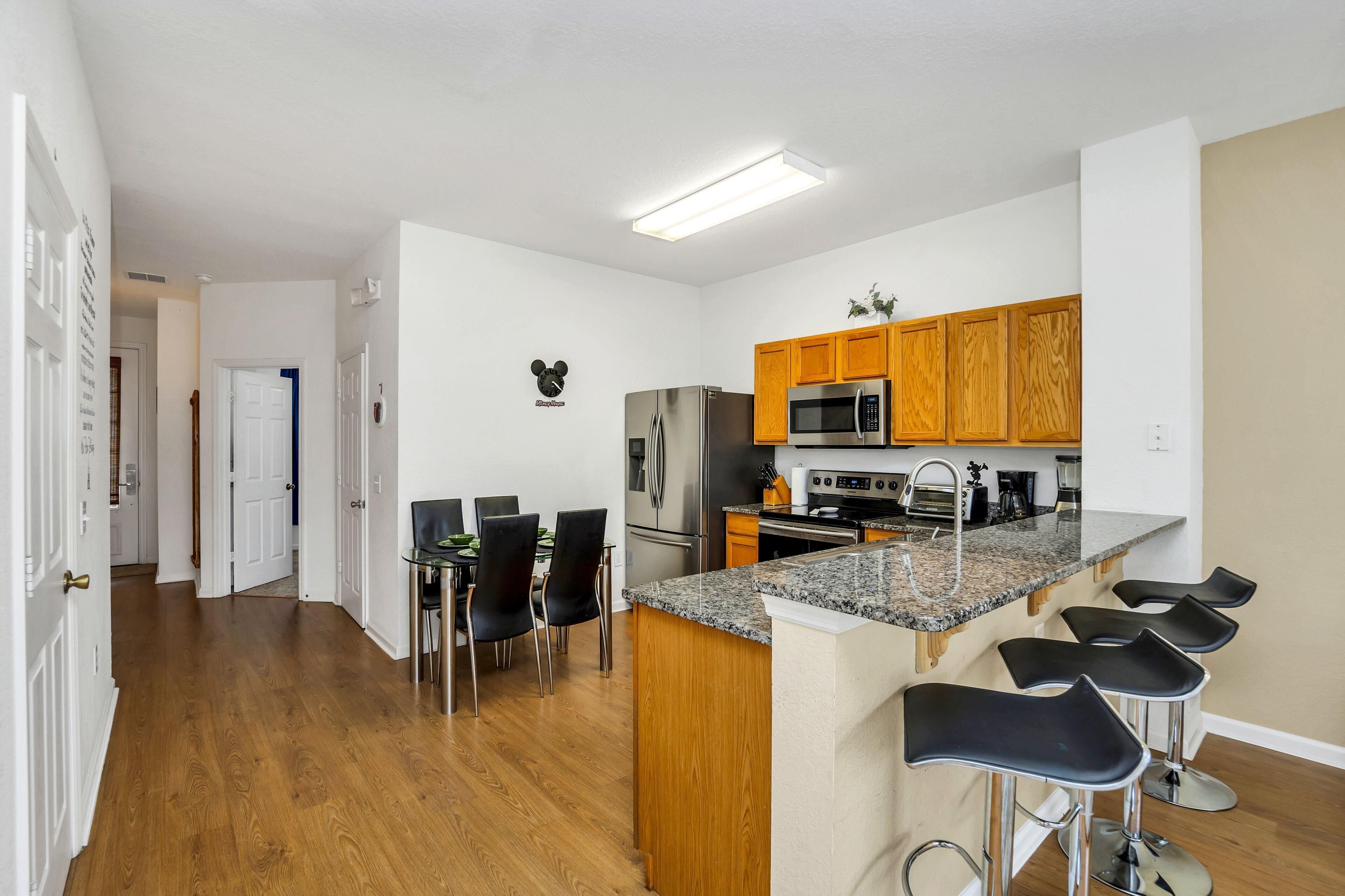 A modern kitchen with wooden cabinets, a granite countertop, and a built-in island with bar stools.