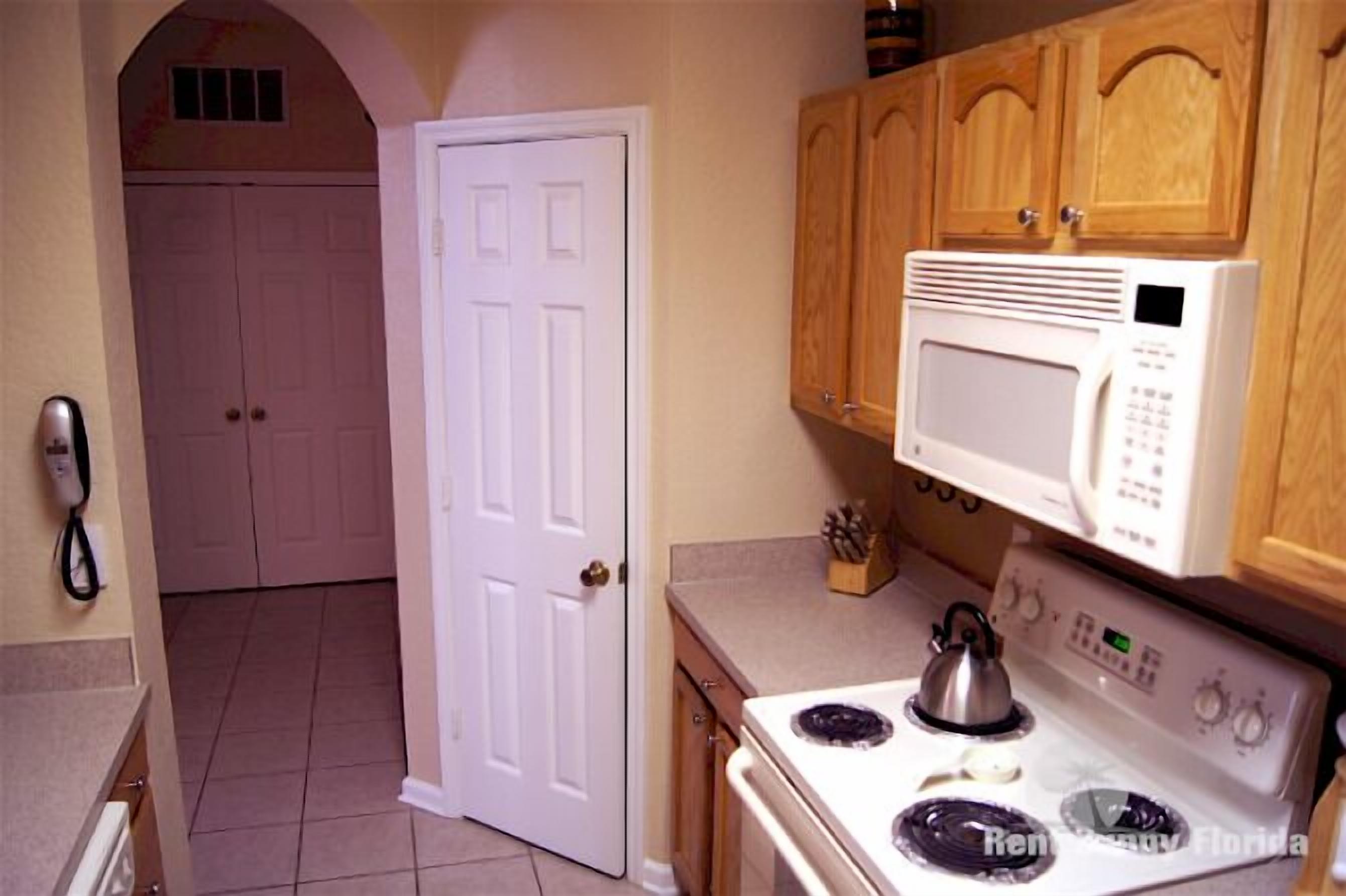 A kitchen with a stove, microwave, and wooden cabinets.