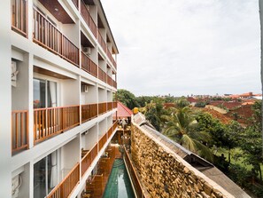 A multi-story hotel with balconies, a swimming pool, and a view of a tropical landscape. - Hadi Poetra Hotel (Kuta)