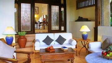 A well-lit living room with a white sofa, two armchairs, a coffee table, and a small side table with a lamp.