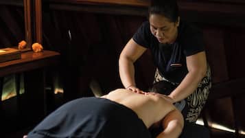 Sessão de massagem em um ambiente com iluminação baixa e painéis de madeira.