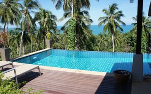 A rectangular swimming pool with clear blue water, surrounded by a wooden deck and palm trees. - NB Villa Daria (Koh Samui)