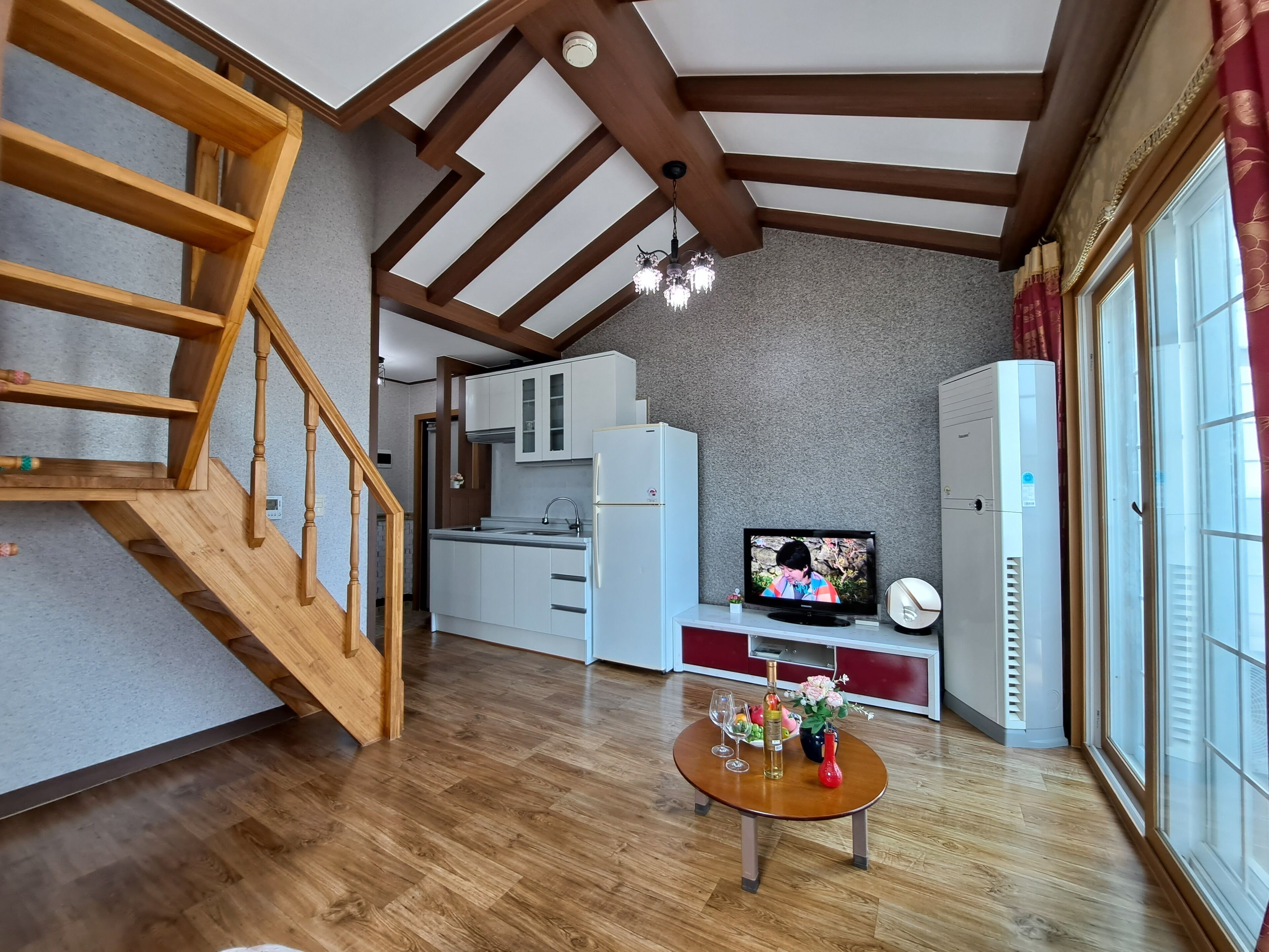 A modern kitchen with white cabinets, a built-in oven, and a TV on a stand.