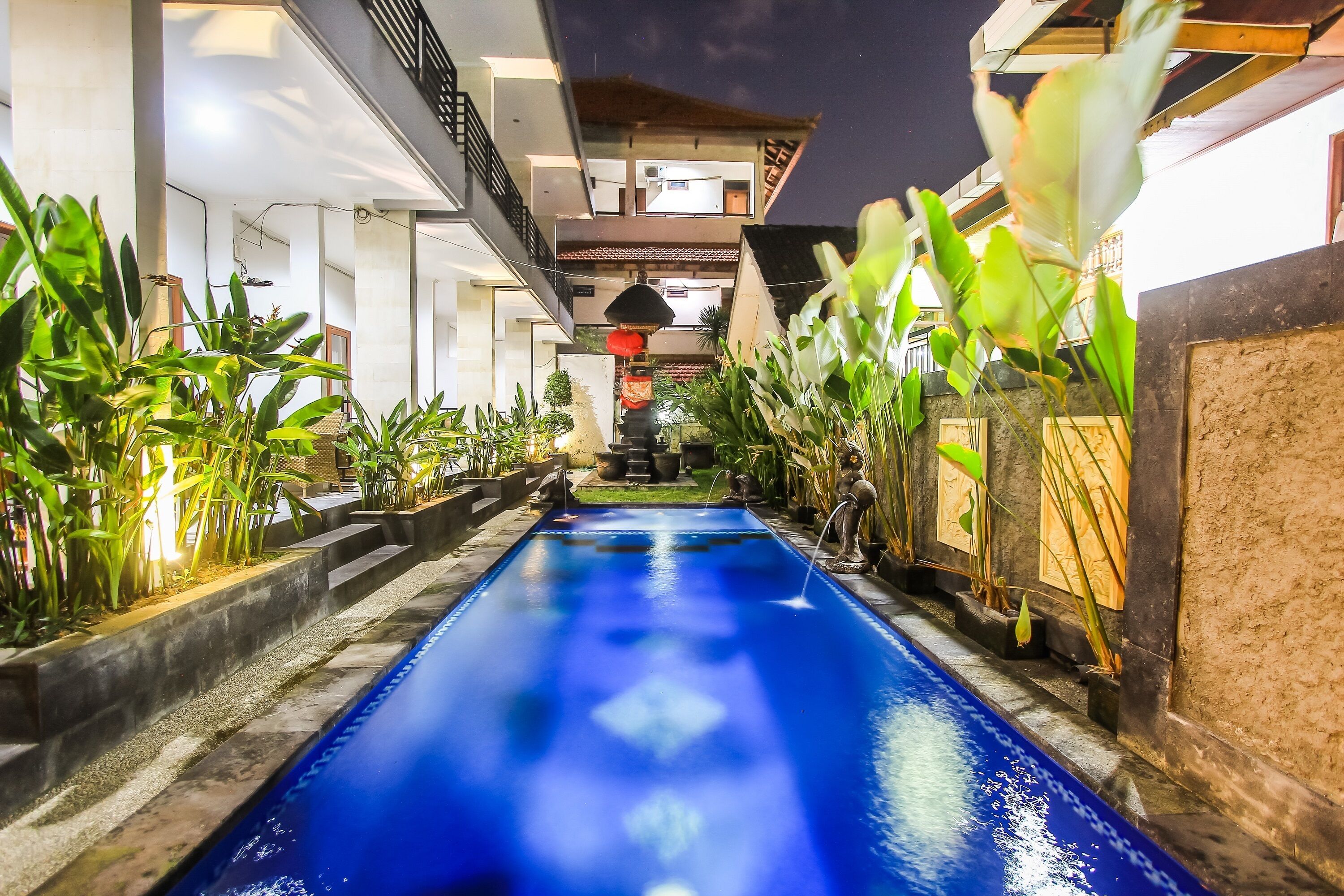 A pool with a blue water feature, surrounded by potted plants and a modern architectural design.
