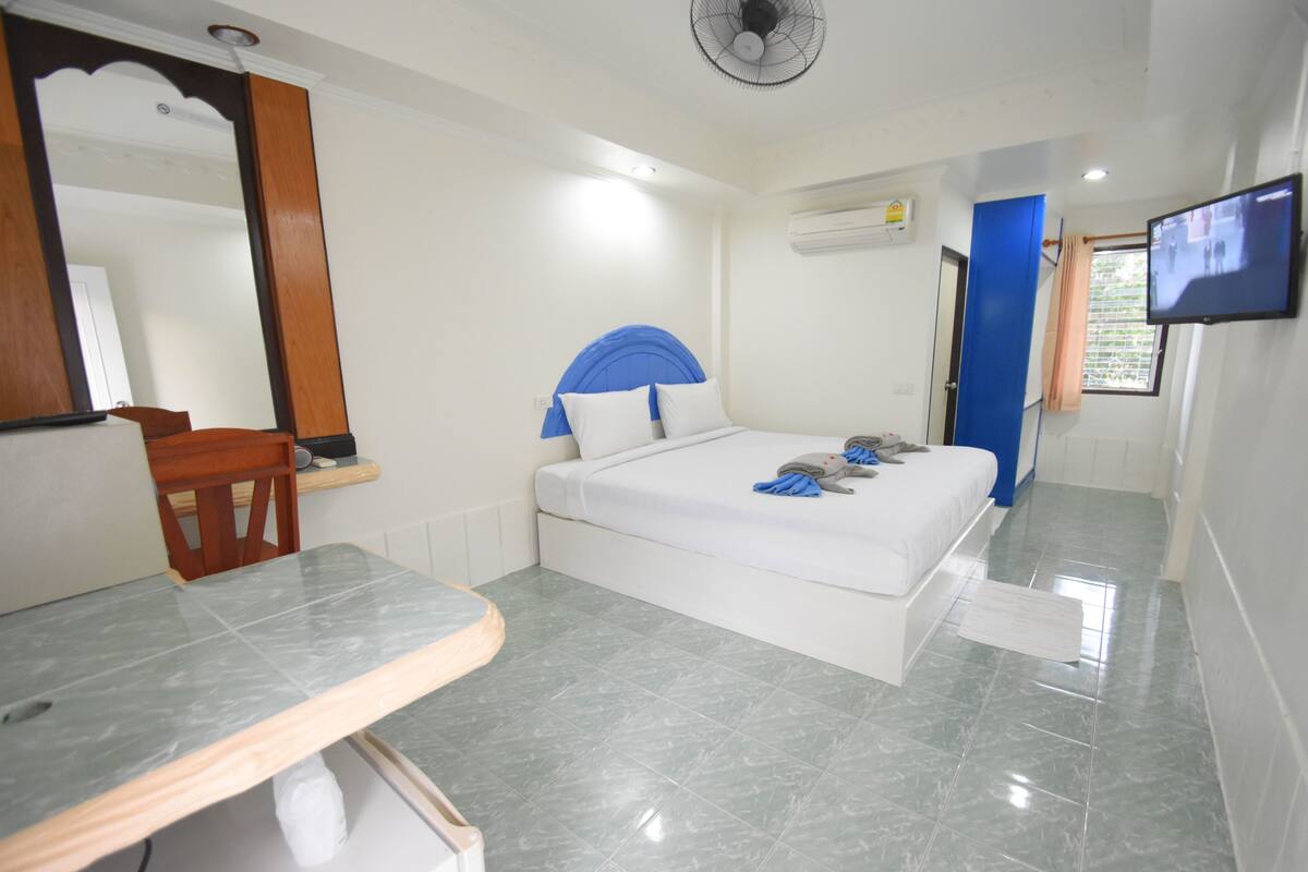 A hotel room with a bed, a desk, a chair, a television, and a mirror.