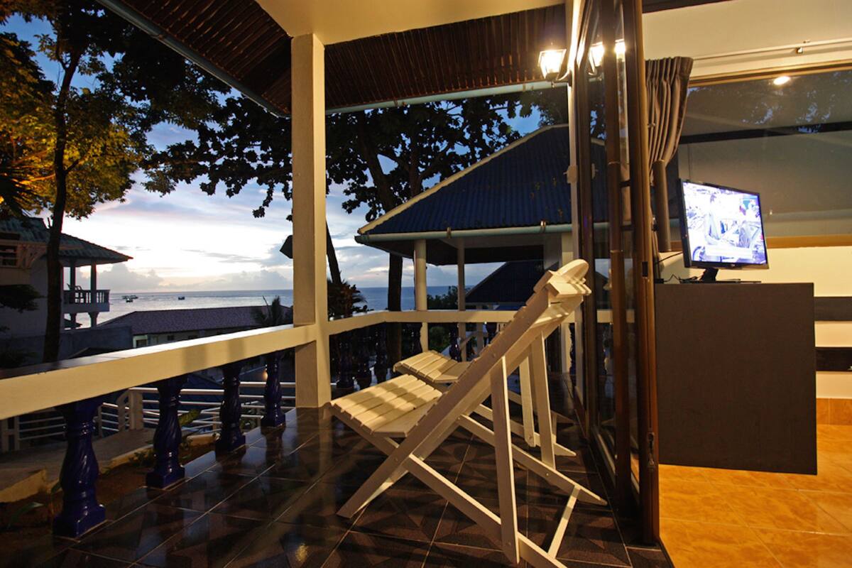 A balcony with a view of the sea, a chair, and a television.