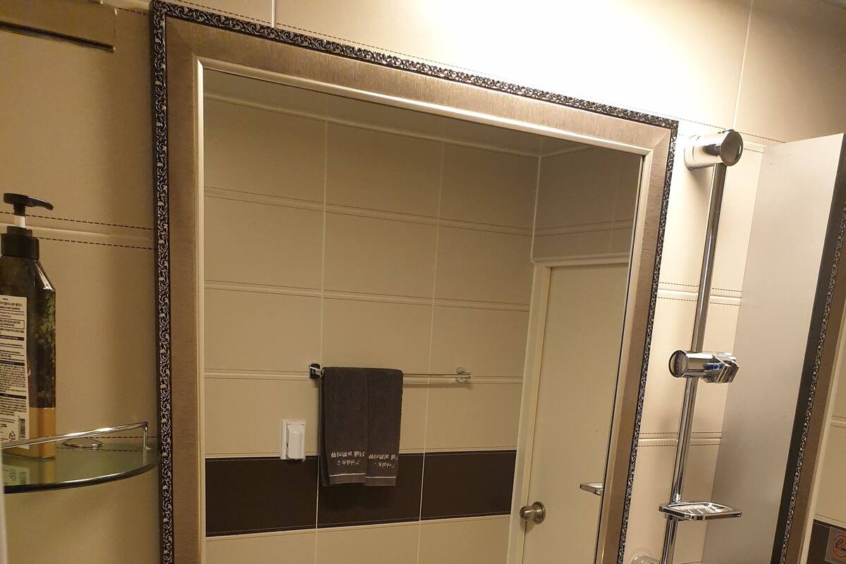 A bathroom with a large mirror, a sink, a toilet, and a shower.