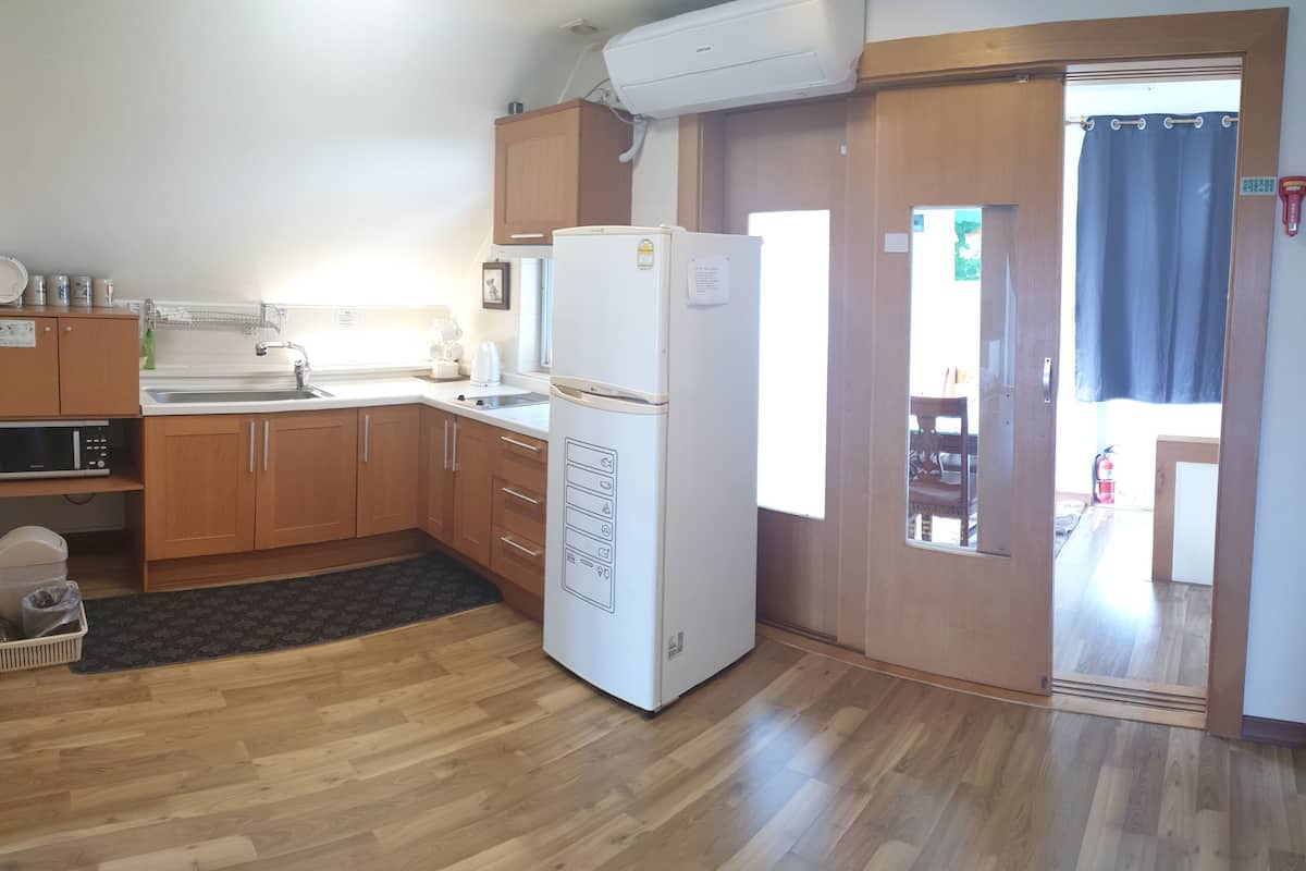 A kitchen with wooden cabinets, a refrigerator, a sink, and a microwave.