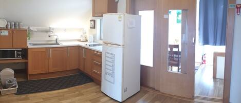 Una cocina compacta con armarios de madera, un refrigerador blanco, un microondas y un lavamanos.