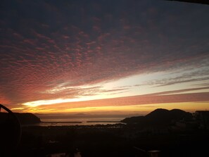 A sunset over a coastal town with visible buildings and hills in the background. - Namhae German Village Neuhaus in Korea (Namhae)