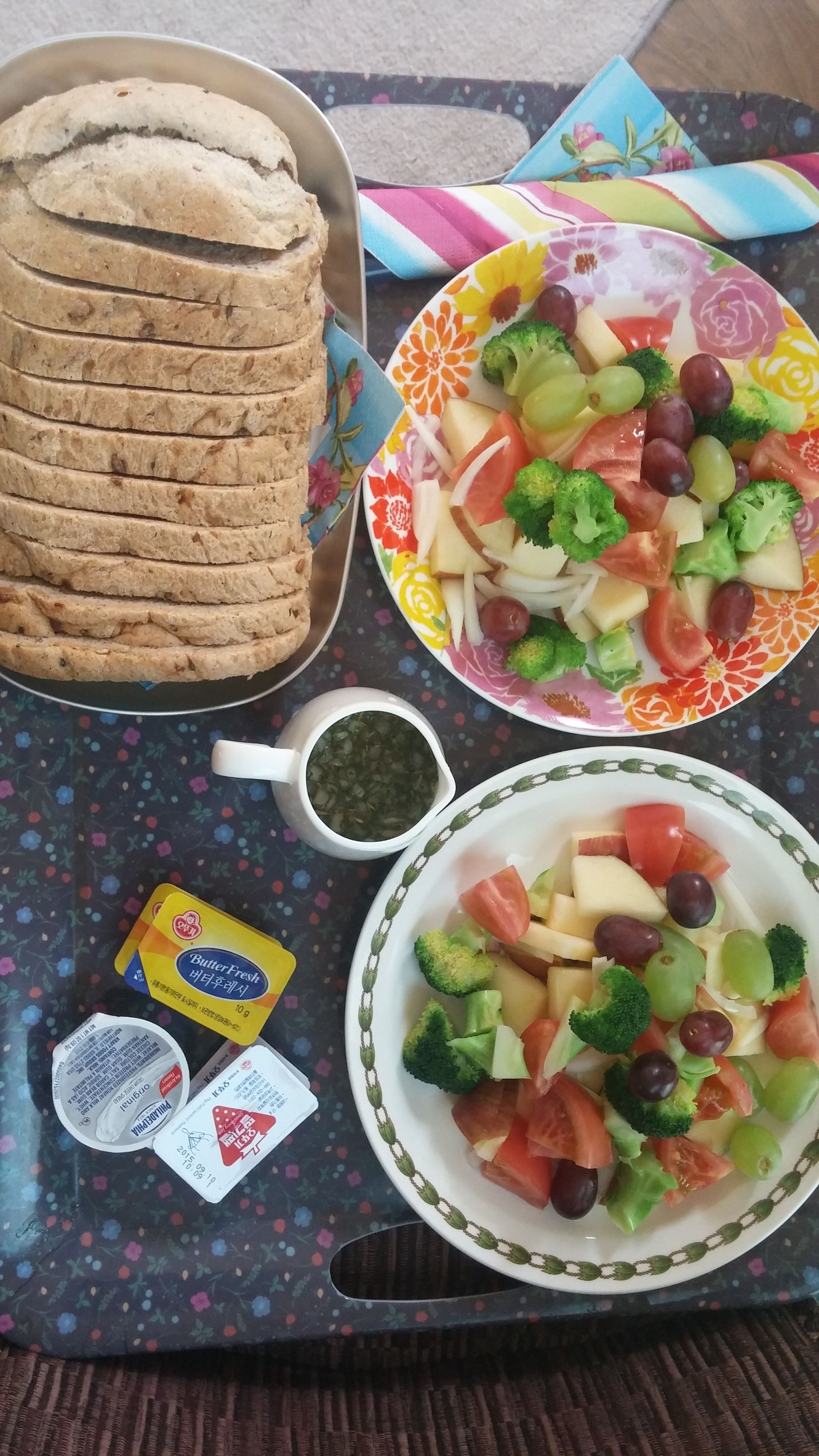 A tray with sliced bread, a bowl of mixed vegetables, and packets of butter and cheese.
