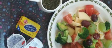 A tray with sliced bread, a bowl of mixed vegetables, and packets of butter and cheese.