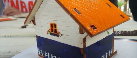 Ein Modellhaus mit weißem Oberteil, blauem Unterteil und einem orangefarbenen Dach.