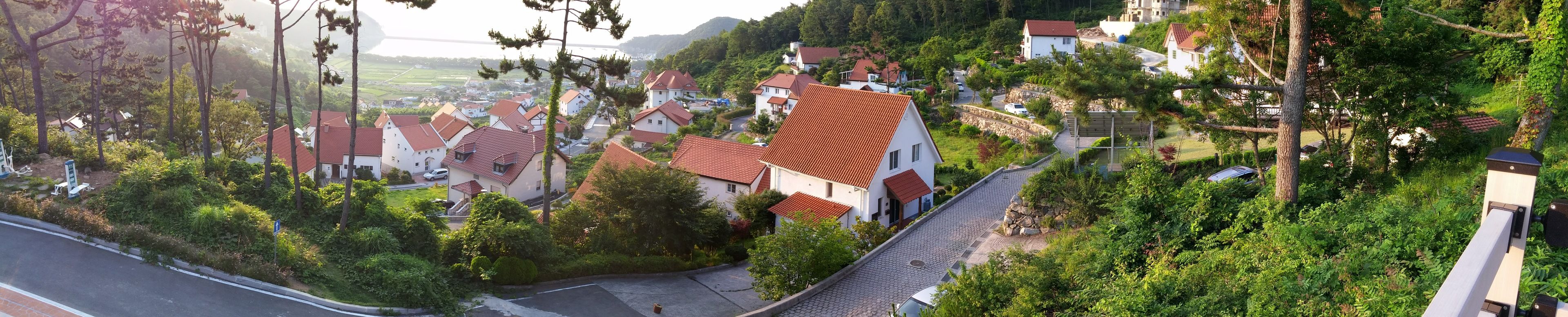 A residential area with houses, a paved road, and a stone wall.