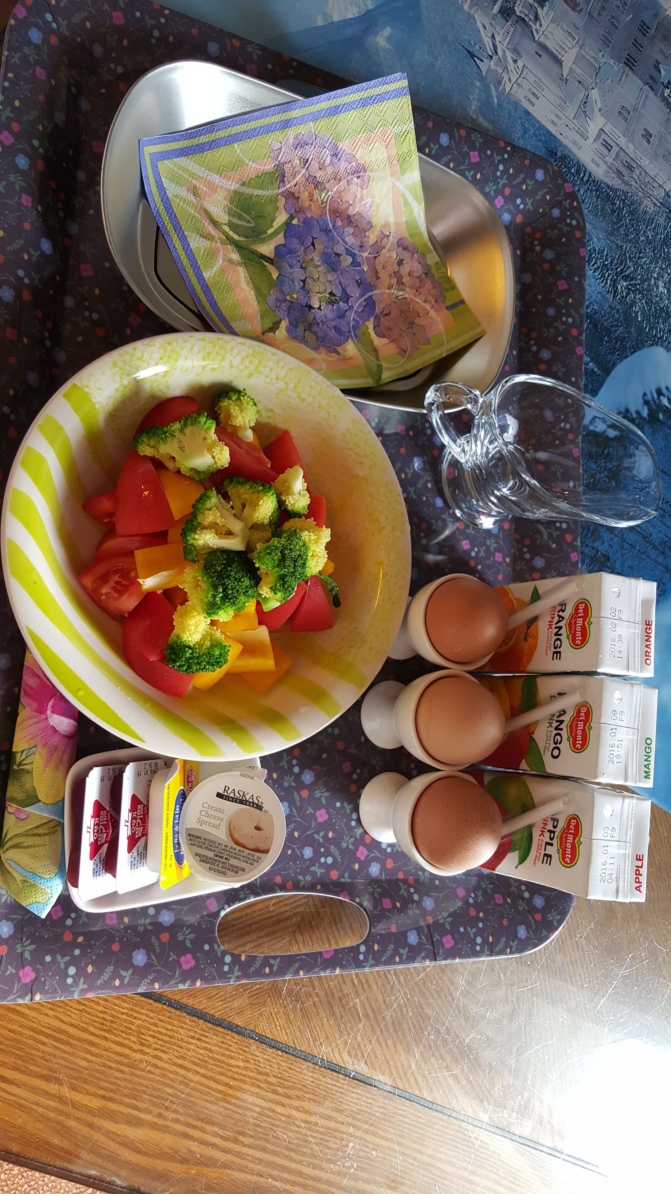 A table with a bowl of mixed vegetables, a pair of shoes, and several cartons of juice.