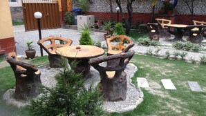 A courtyard with rustic wooden tables and chairs, surrounded by gravel and small plants. - Andes House (Kathmandu)
