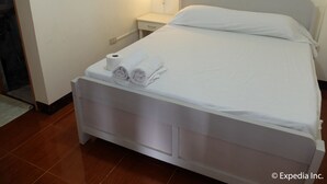 A neatly made bed with white linens and towels, a bedside table with a lamp, and a wall socket. - Centrium Condominium Hotel (Angeles City)