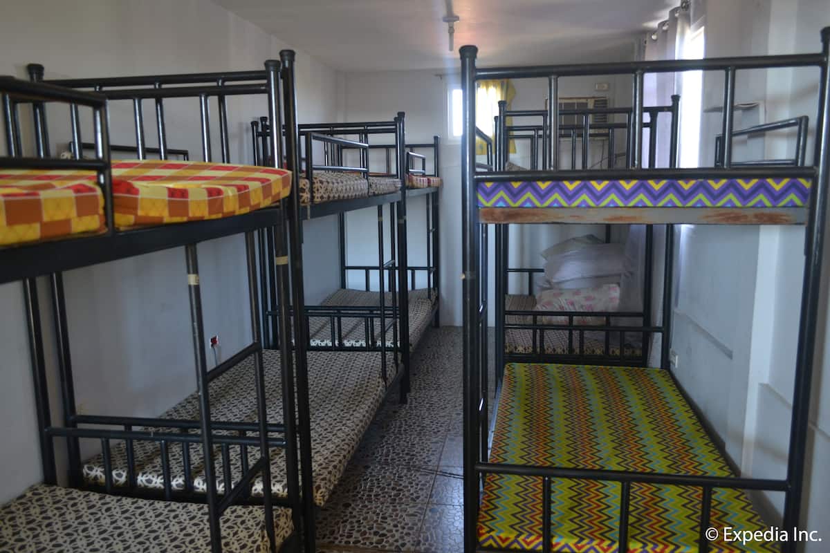 Un dormitorio con literas, pisos de baldosas y un ventanal con cortinas.