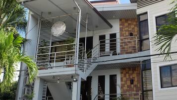 A multi-story building with a balcony, staircases, and a hanging spherical light fixture.