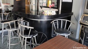 A bar area with a black counter, bar stools, and a 'WELCOME' sign. - Centrium Condominium Hotel (Angeles City)