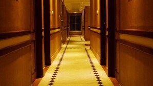 A long, narrow hotel corridor with a patterned floor and wooden walls. - Sea Shell Residence (Dhaka)