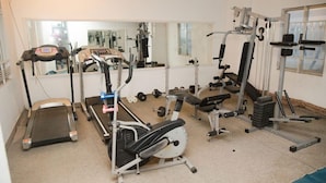 A gym with cardio equipment, weight machines, and free weights. - Sea Shell Residence (Dhaka)