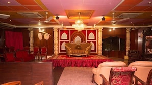 A grand hall with a stage, ornate columns, and a chandelier. - Sea Shell Residence (Dhaka)
