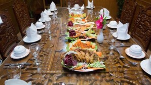 A long dining table set for a meal with various dishes, glasses, and napkins. - Sea Shell Residence (Dhaka)
